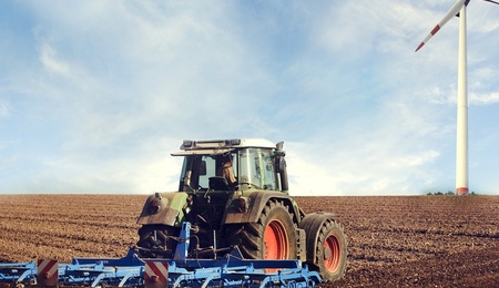 Traktor auf einem Feld mit Windrad
