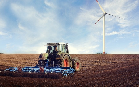 Traktor auf einem Feld mit Windrad